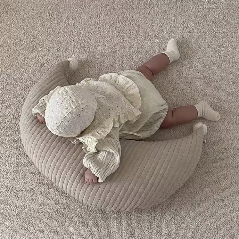 Bébé allongé sur un coussin lune beige Be'Lune, conçu pour soutenir l’éveil, le confort et le repos en toute sécurité.