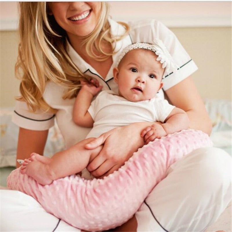 Maman tenant son bébé avec le coussin d’allaitement Be'Move rose pour un soutien confortable et sécurisé