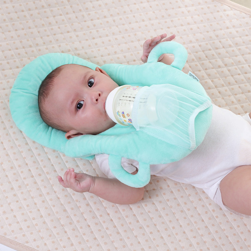 Nourrisson allongé confortablement avec le coussin Be'Tender vert, tenant son biberon sans aide pour une tétée sereine.