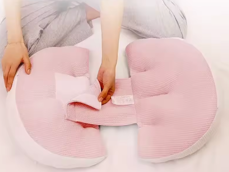 Ajustement du coussin Be'Link rose de BEBLY, conçu pour offrir un maintien modulable et un confort optimal pendant la grossesse ou l’allaitement.