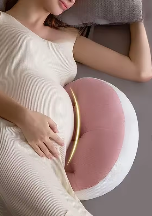 Femme enceinte allongée avec un coussin Be'Link rose de BEBLY, conçu pour soulager les lombaires et soutenir le ventre durant la grossesse.