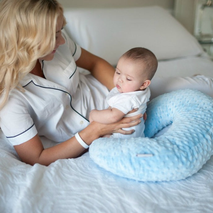 Maman utilisant le coussin d’allaitement portable Be'Move pour soutenir son bébé confortablement sur un lit blanc