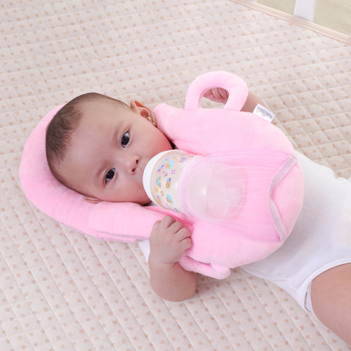 Bébé allongé utilisant le coussin Be'Tender rose pour tenir son biberon sans assistance, confort et autonomie pour l’allaitement.