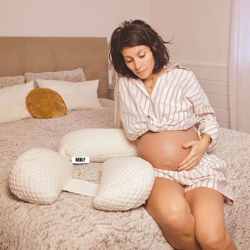 Femme enceinte utilisant un coussin de grossesse ergonomique sur un lit BEBLY
